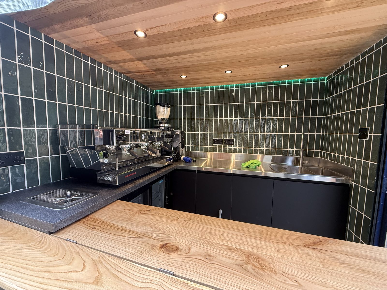 Inside a unit: green tiled walls, timber ceiling, stainless counter and espresso machine